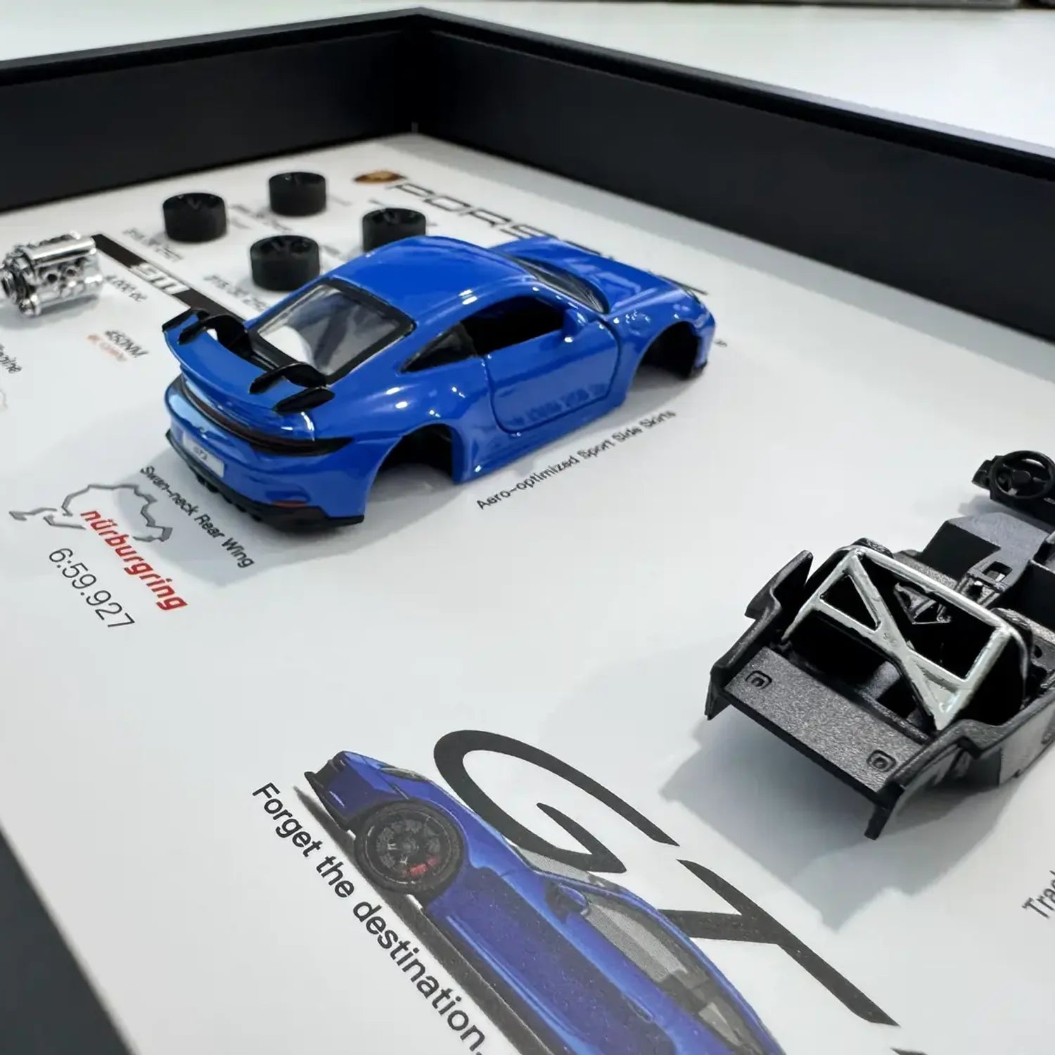 Porsche 911 GT3 992 Shark Blue Deconstructed Frame — macro detail of the Shark Blue body shell, roll cage chassis and swan-neck rear wing
