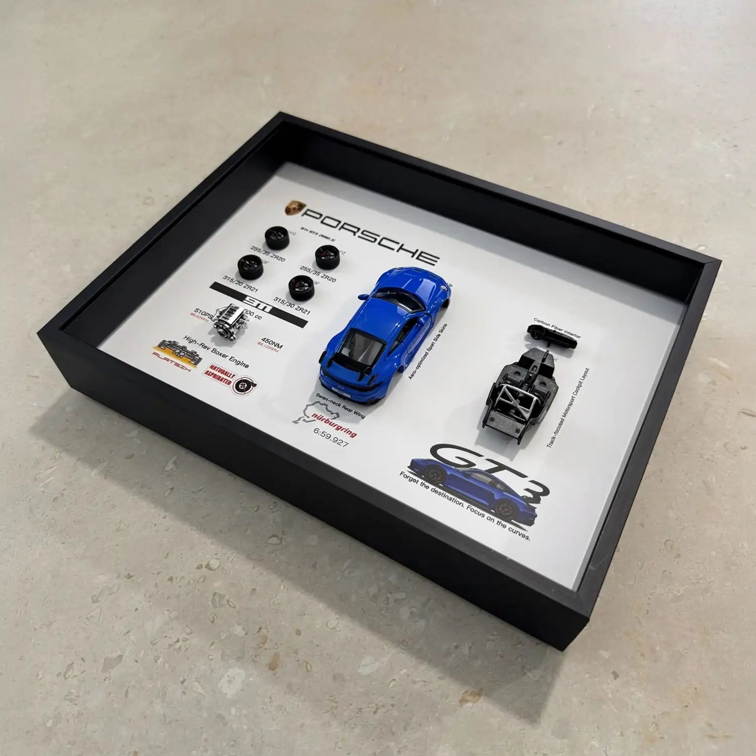 Porsche 911 GT3 992 Shark Blue Deconstructed Frame — laid flat on pale stone at an angle, showing the depth of the shadow box