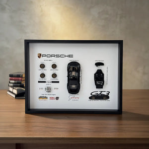 Porsche 911 GT3 992 Deconstructed Frame — standing on a walnut desk beside stacked books under warm wall light