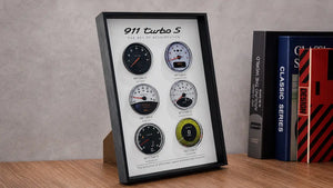 Porsche 911 Turbo S Tachometer Evolution 3D Framed Display — standing on a wood desk beside books, showing 3D layered depth